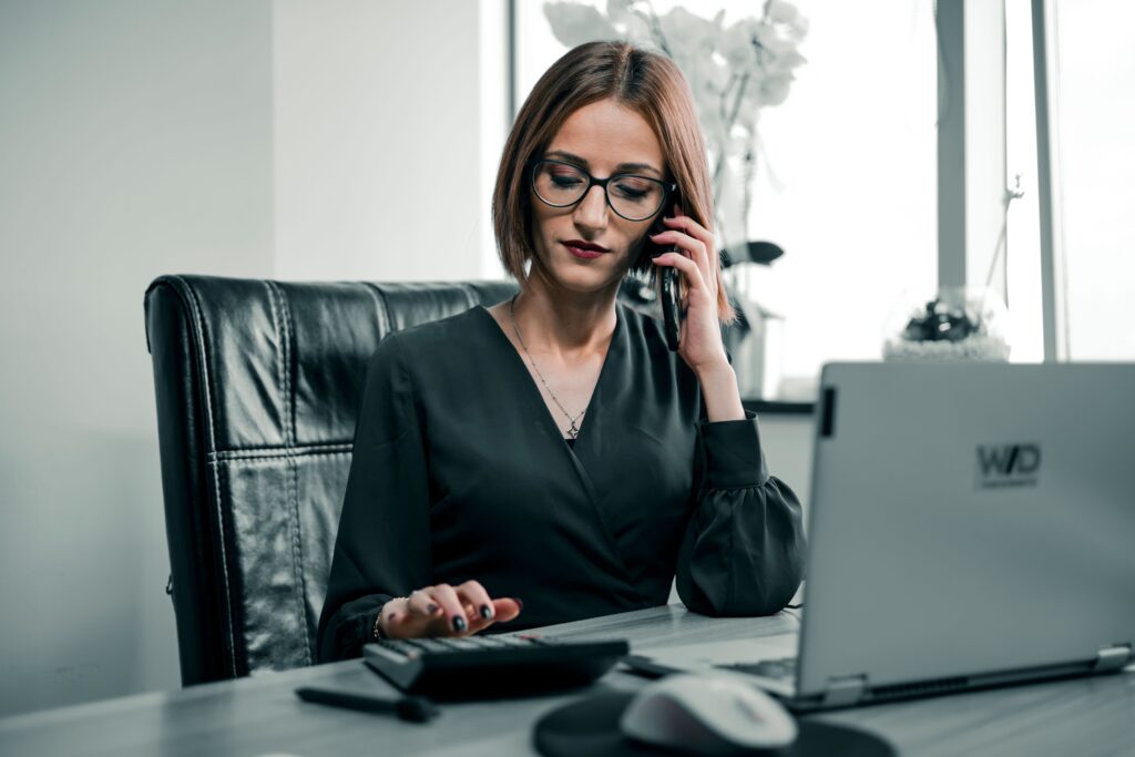 pexels photo 17682882 17682882 Businesswoman multitasking with a phone and calculator at a desk, showcasing office productivity.