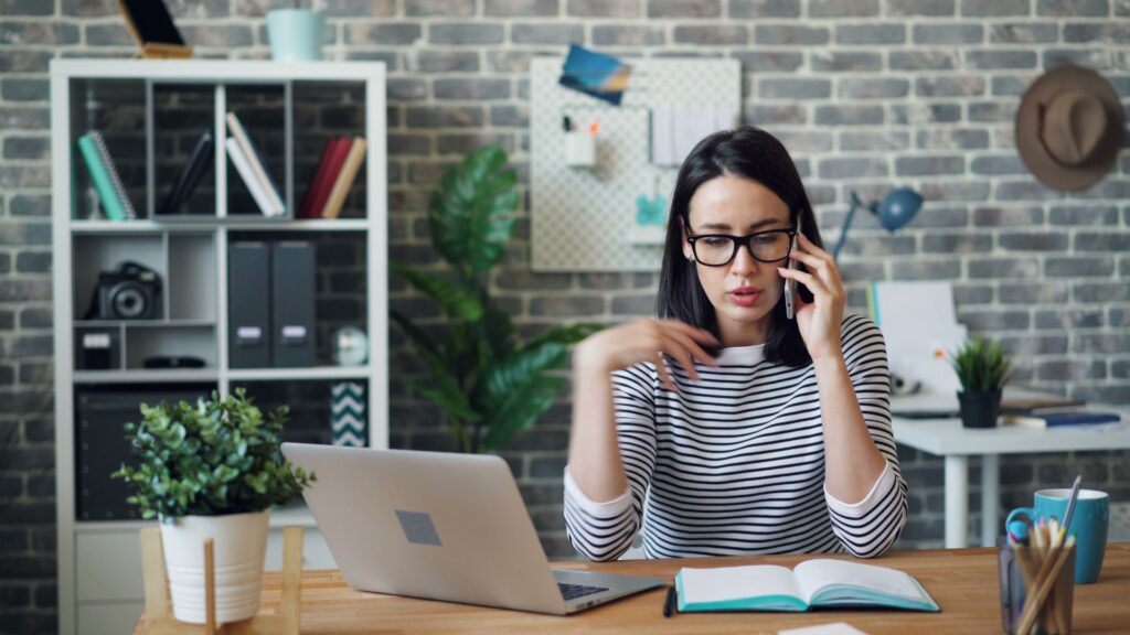 pexels photo 22046237 22046237 Focused woman multitasking with laptop and phone in a cozy modern office setting.