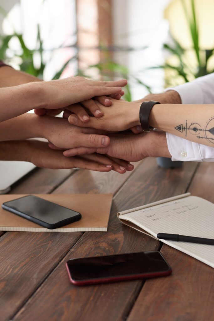 pexels photo 3184431 3184431 Hands from a diverse team stack on a table symbolizing unity and teamwork in a modern office setting.