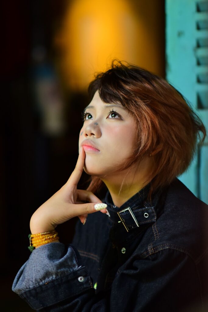 pexels photo 37952524 37952524 Portrait of a young woman in denim, pondering deeply under moody lights.