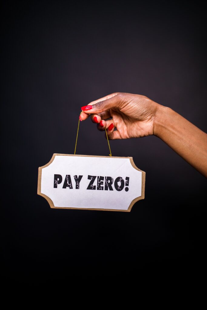 pexels photo 7563677 7563677 A hand holding a sign 'PAY ZERO!' against a dark backdrop, ideal for business and marketing concepts.